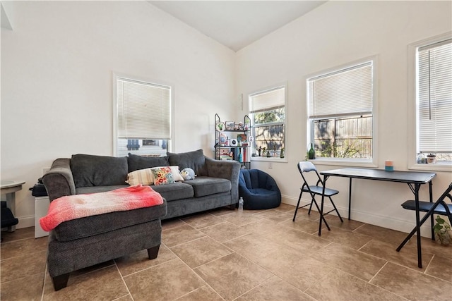 living room with lofted ceiling, light tile patterned flooring, and baseboards