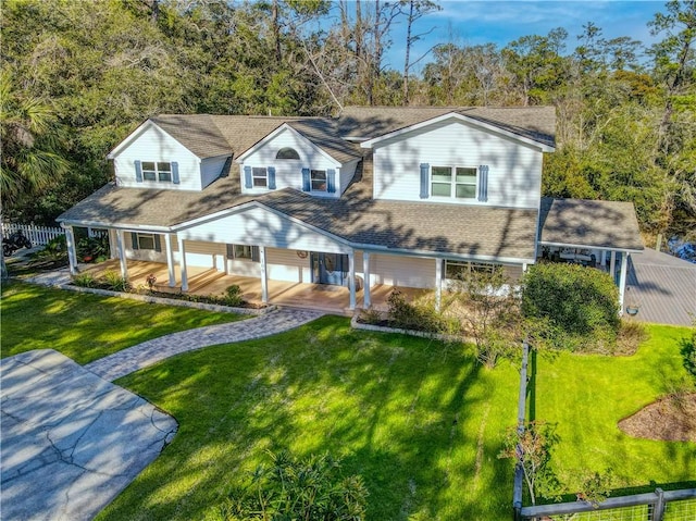 view of front of property with driveway, roof with shingles, and a front yard