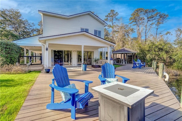 wooden terrace featuring a fire pit and a gazebo