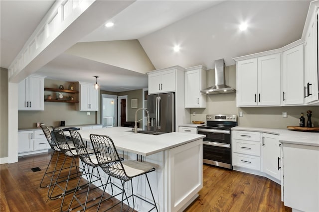 kitchen with white cabinetry, appliances with stainless steel finishes, an island with sink, and wall chimney exhaust hood