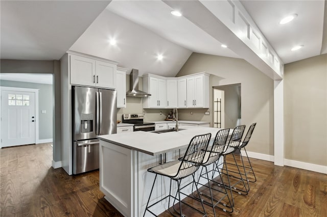 kitchen with wall chimney exhaust hood, sink, a center island with sink, stainless steel appliances, and white cabinets