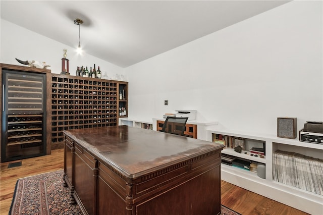 wine room featuring lofted ceiling, beverage cooler, and light hardwood / wood-style floors