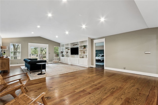 living room featuring built in shelves, lofted ceiling, and wood-type flooring