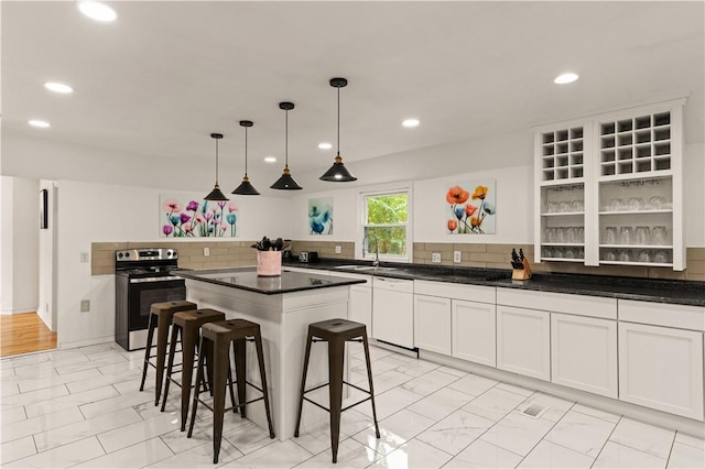 kitchen with a breakfast bar area, decorative backsplash, stainless steel electric range, white dishwasher, and a sink