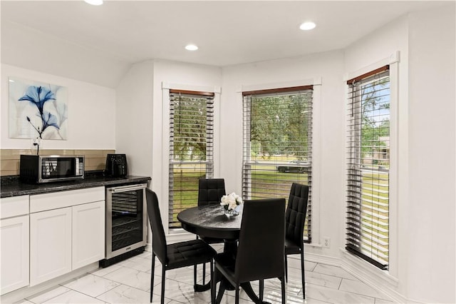 dining space featuring beverage cooler, recessed lighting, and marble finish floor