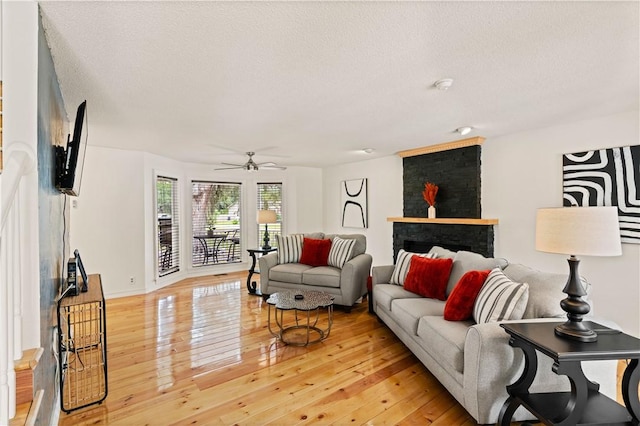 living room with baseboards, light wood-style floors, ceiling fan, and a textured ceiling