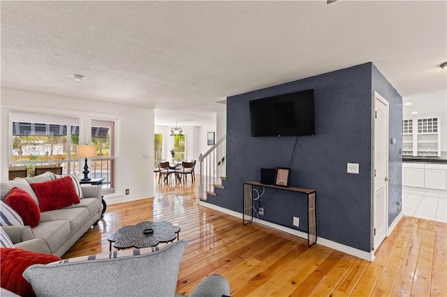 living room featuring baseboards, light wood-style floors, and a textured ceiling