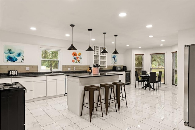 kitchen with a sink, dark countertops, marble finish floor, and freestanding refrigerator