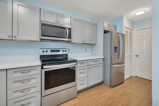 kitchen featuring stainless steel appliances, light hardwood / wood-style floors, and gray cabinetry