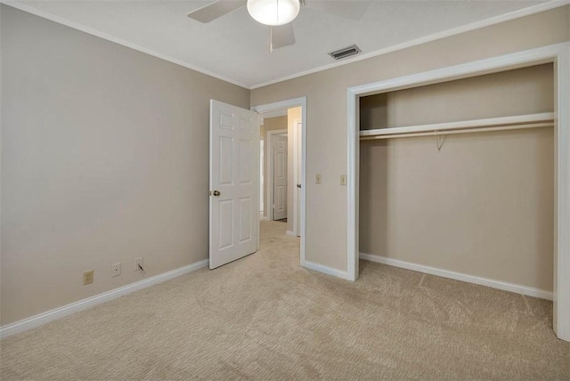 unfurnished bedroom with crown molding, ceiling fan, a closet, and light carpet