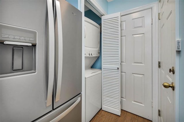 laundry area with stacked washer / drying machine and hardwood / wood-style flooring