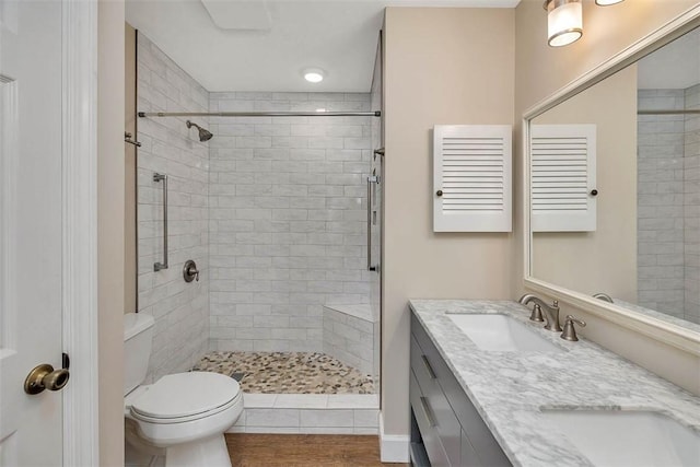 bathroom with tiled shower, hardwood / wood-style floors, vanity, and toilet