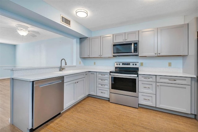 kitchen featuring kitchen peninsula, sink, light wood-type flooring, and appliances with stainless steel finishes