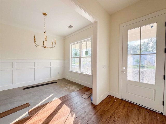 1105 Tranquility Pl NE, Townsend, GA 31331 - doorway with a chandelier, wood finished floors, a decorative wall, and a wainscoted wall