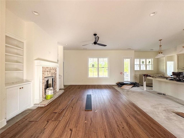 1105 Tranquility Pl NE, Townsend, GA 31331 - living area with a fireplace, a ceiling fan, wood finished floors, built in features, and baseboards