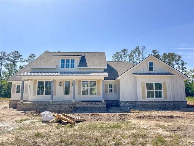 view of front of property featuring a shingled roof, board and batten siding, a standing seam roof, covered porch, and metal roof