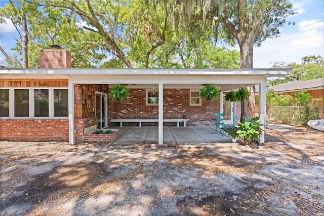 back of house featuring brick siding and a chimney