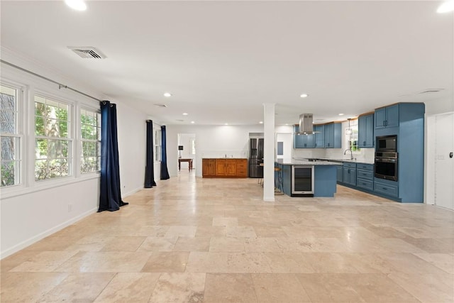 kitchen featuring light countertops, beverage cooler, blue cabinetry, island exhaust hood, and visible vents