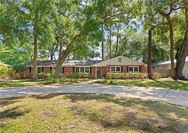 ranch-style home with brick siding, fence, a front yard, and concrete driveway