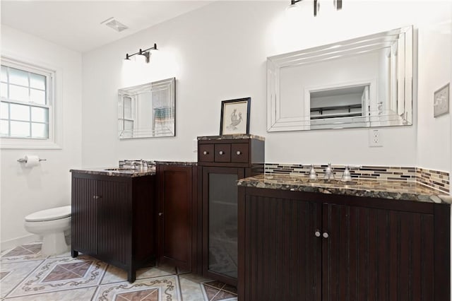 bathroom featuring visible vents, tile patterned floors, toilet, and two vanities