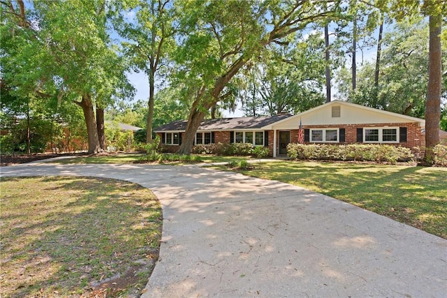 single story home with concrete driveway, brick siding, and a front yard