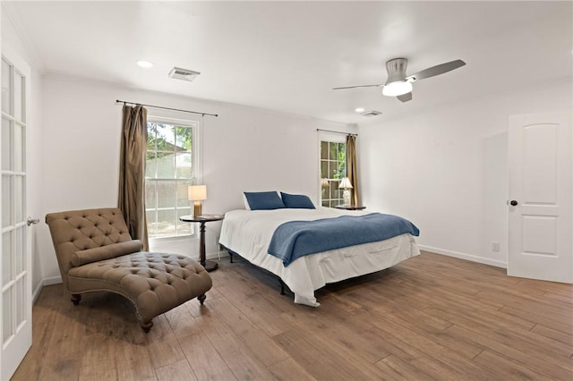 bedroom with baseboards, a ceiling fan, wood finished floors, and visible vents