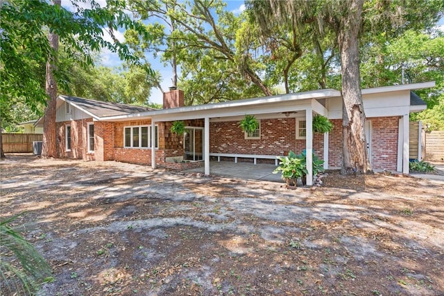 view of front of home with brick siding, fence, and a chimney