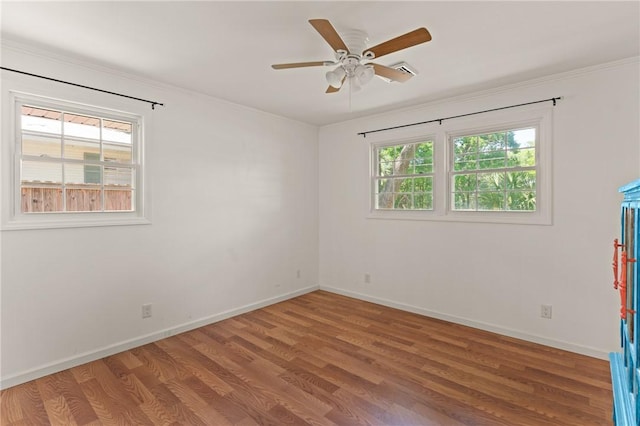 empty room featuring crown molding, baseboards, a ceiling fan, and wood finished floors