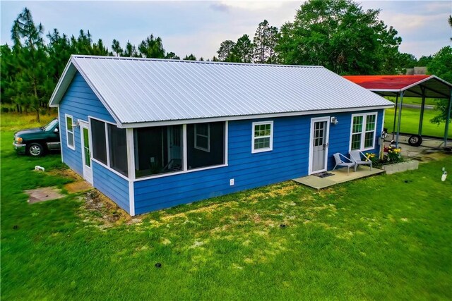 20 Marla St, Hoboken, GA 31542 - rear view of property with metal roof, a lawn, a carport, and a sunroom