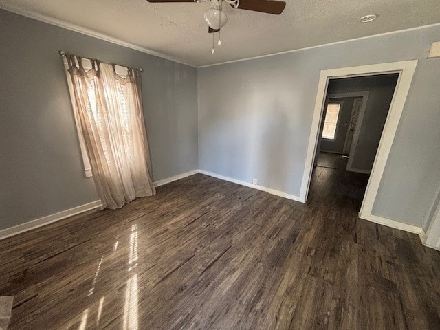 empty room featuring ceiling fan, crown molding, and dark wood-type flooring