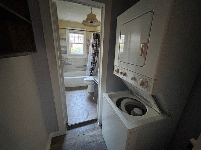 laundry room featuring hardwood / wood-style floors and stacked washer and dryer