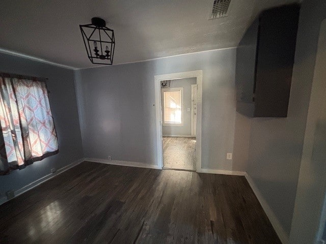 unfurnished dining area featuring dark wood-type flooring and a notable chandelier