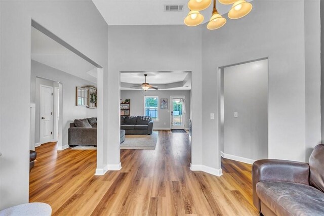 foyer featuring ceiling fan with notable chandelier and light wood-type flooring