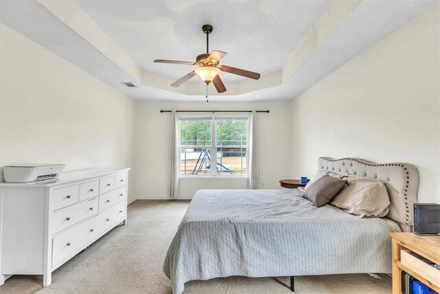 bedroom featuring a tray ceiling, ceiling fan, and light carpet