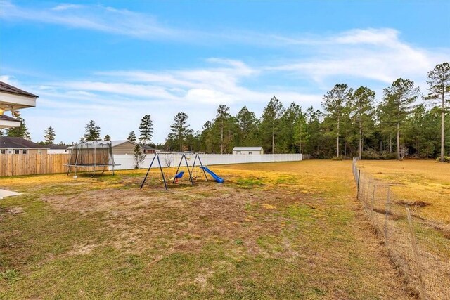 view of yard with a playground and a trampoline