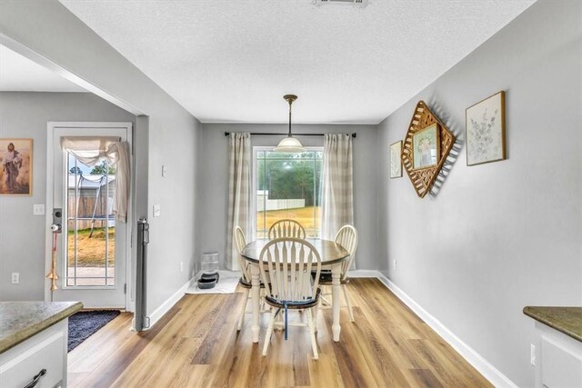 dining area featuring a textured ceiling and light wood-type flooring