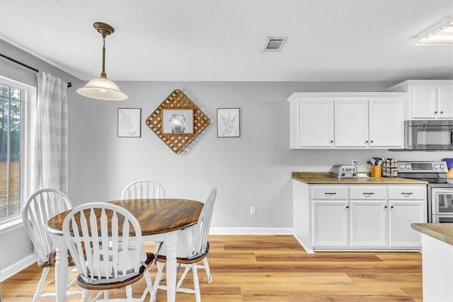 dining area with a textured ceiling and light hardwood / wood-style flooring