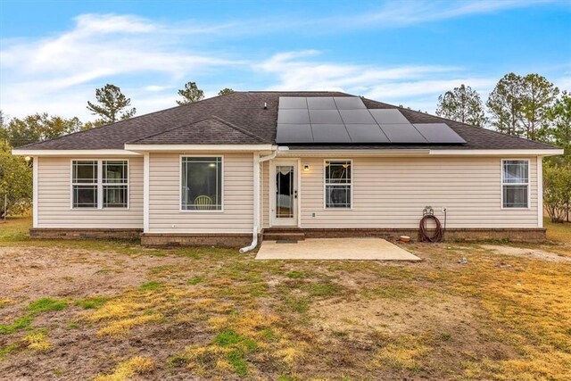 back of house featuring solar panels, a patio area, and a yard