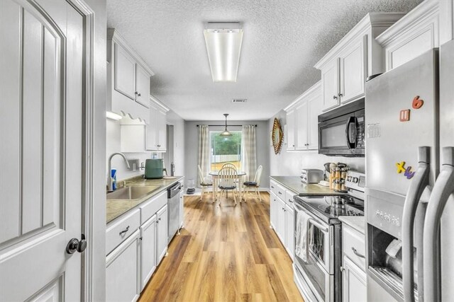 kitchen with white cabinetry, sink, a textured ceiling, appliances with stainless steel finishes, and light wood-type flooring