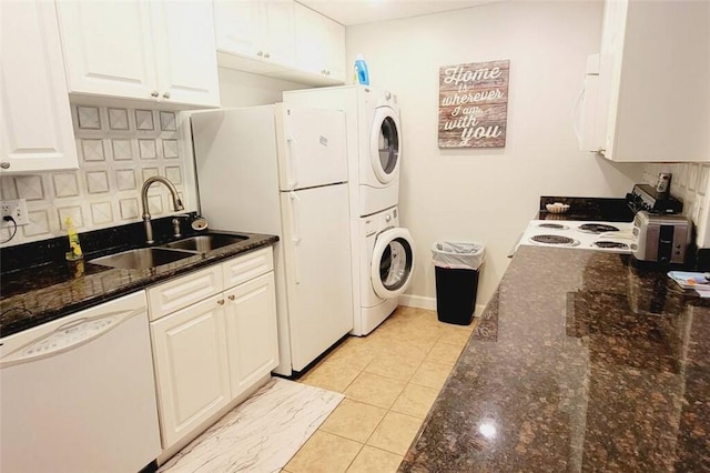 laundry area featuring sink, light tile patterned floors, and stacked washer and dryer