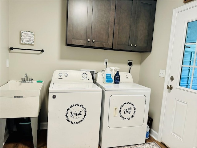 clothes washing area with cabinets, hardwood / wood-style floors, washer and dryer, and sink