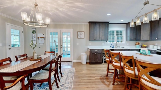 dining space featuring light hardwood / wood-style floors, an inviting chandelier, plenty of natural light, and ornamental molding