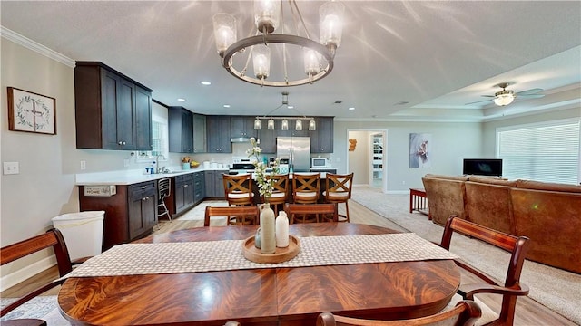 dining area with sink, light hardwood / wood-style floors, ceiling fan with notable chandelier, and ornamental molding