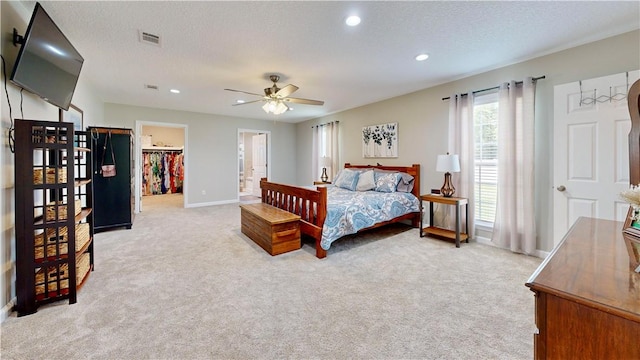 carpeted bedroom featuring ceiling fan, a spacious closet, a textured ceiling, and a closet