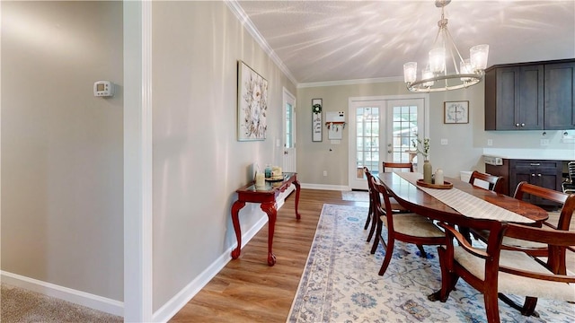 dining space featuring ornamental molding, french doors, light hardwood / wood-style floors, and an inviting chandelier