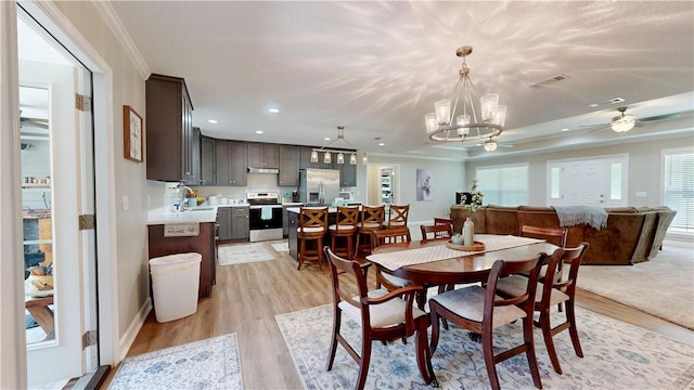 dining space featuring light hardwood / wood-style floors, sink, a healthy amount of sunlight, and crown molding
