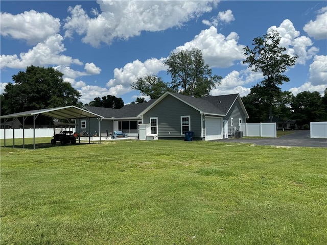 rear view of house with a yard, a garage, a carport, and cooling unit