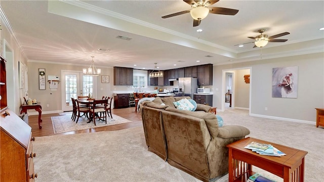 living room featuring light hardwood / wood-style flooring, ceiling fan with notable chandelier, and ornamental molding