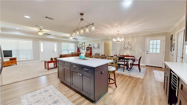 kitchen featuring ceiling fan with notable chandelier, a kitchen island, light hardwood / wood-style floors, and hanging light fixtures