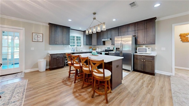 kitchen with dark brown cabinets, light hardwood / wood-style flooring, hanging light fixtures, and appliances with stainless steel finishes